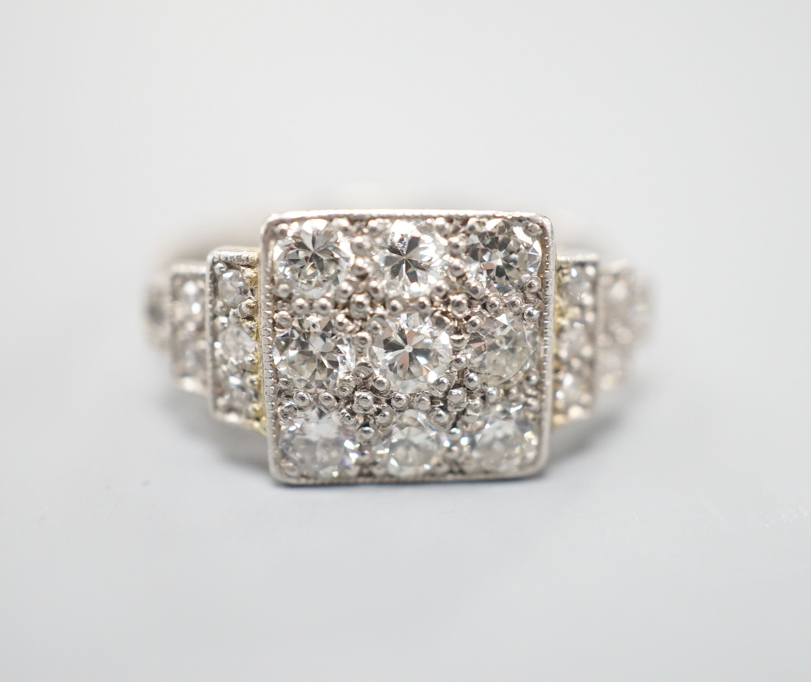 An Art Deco style white metal and nine stone diamond set tablet ring, with diamond set stepped shoulders, size K, gross weight 3.2 grams.